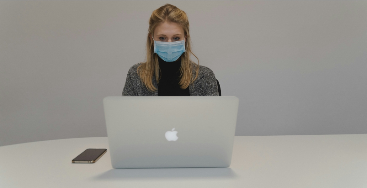 Woman sitting in front of a computer wearing a mask