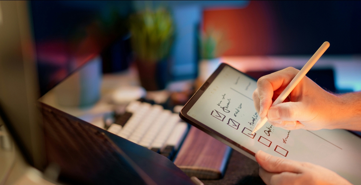 Photograph of a man writing on a tablet