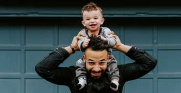 Photograph of a father carrying his son on his shoulders