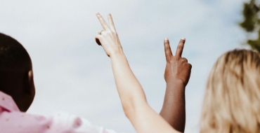 Photo of a man and a woman raising two fingers in the air