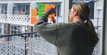 photograph of a girl in her house writing on post it notes
