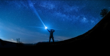 Photograph of a man with a lamp in the mountains